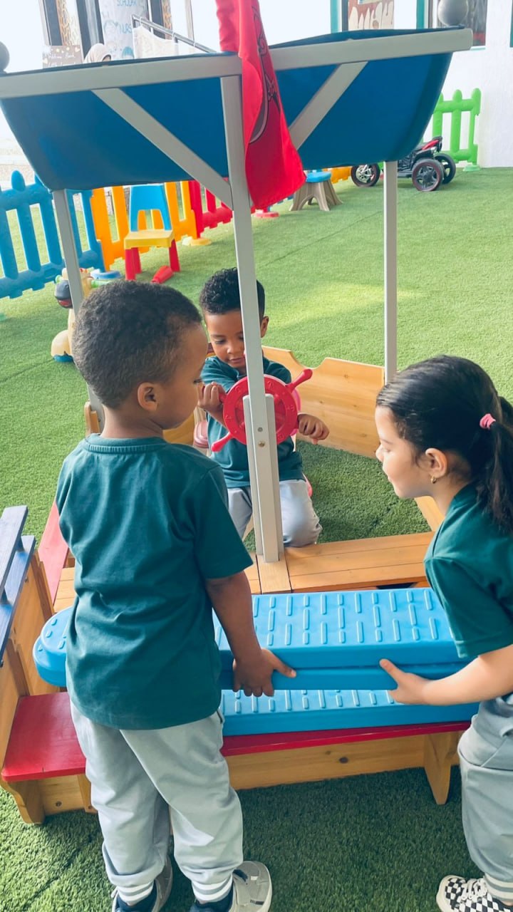 Outdoor wooden pirate-ship play structure on green turf at Early Scholars Nursery, Ajman